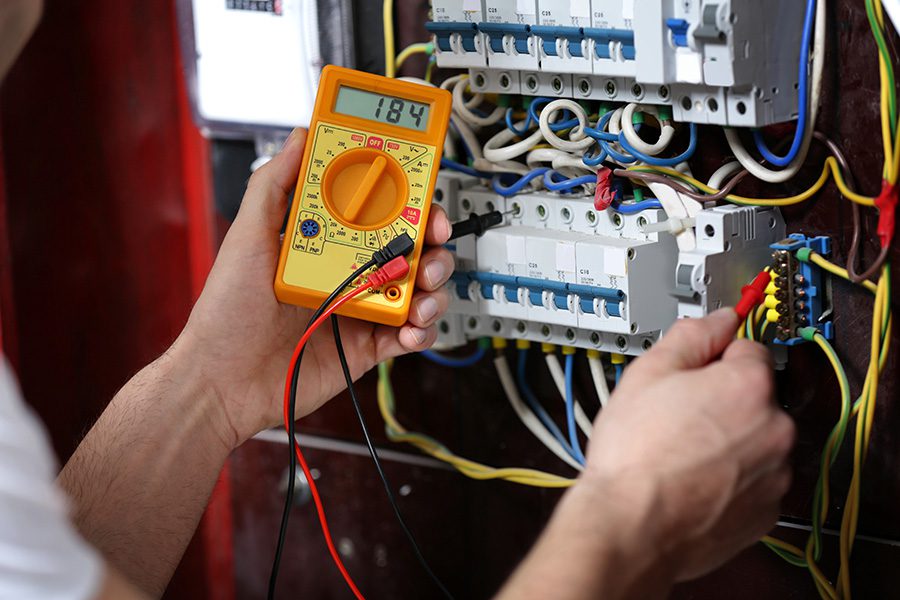 Electrician measuring voltage in distribution board